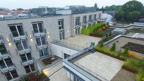 Un bâtiment moderne doté de nombreux balcons, d’un jardin sur le toit et d’une terrasse plate.