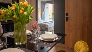 Une table à manger dressée avec des assiettes, des verres et un vase rempli de tulipes jaunes.