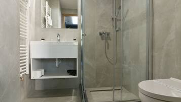 A modern bathroom with a glass-enclosed shower, a white sink, and a toilet.