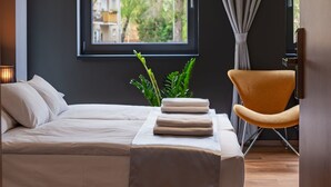 Une chambre à coucher moderne avec un lit, une chaise, une fenêtre donnant sur des arbres et un rideau.