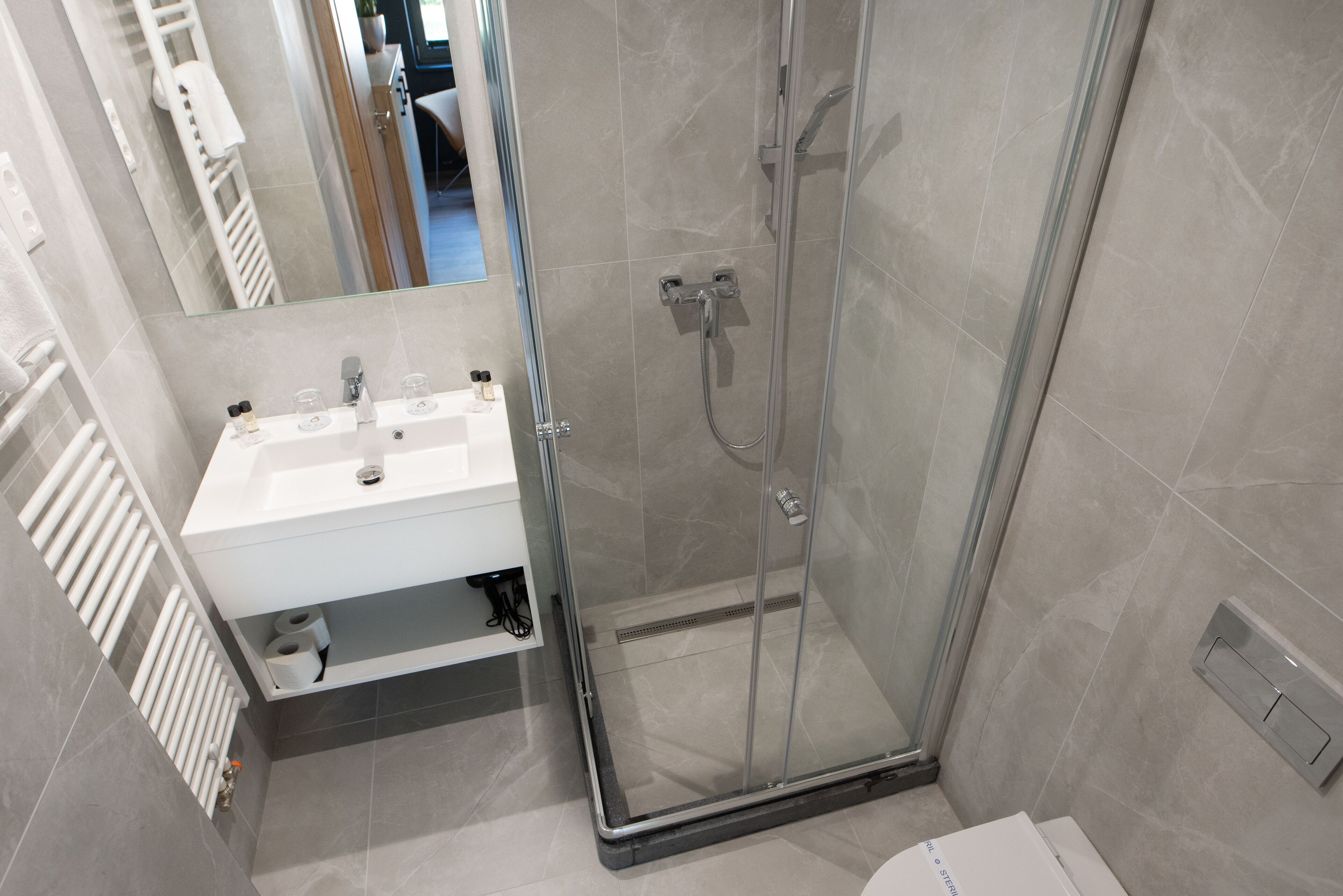 A modern bathroom with a glass-enclosed shower, a white sink, and a mirror.