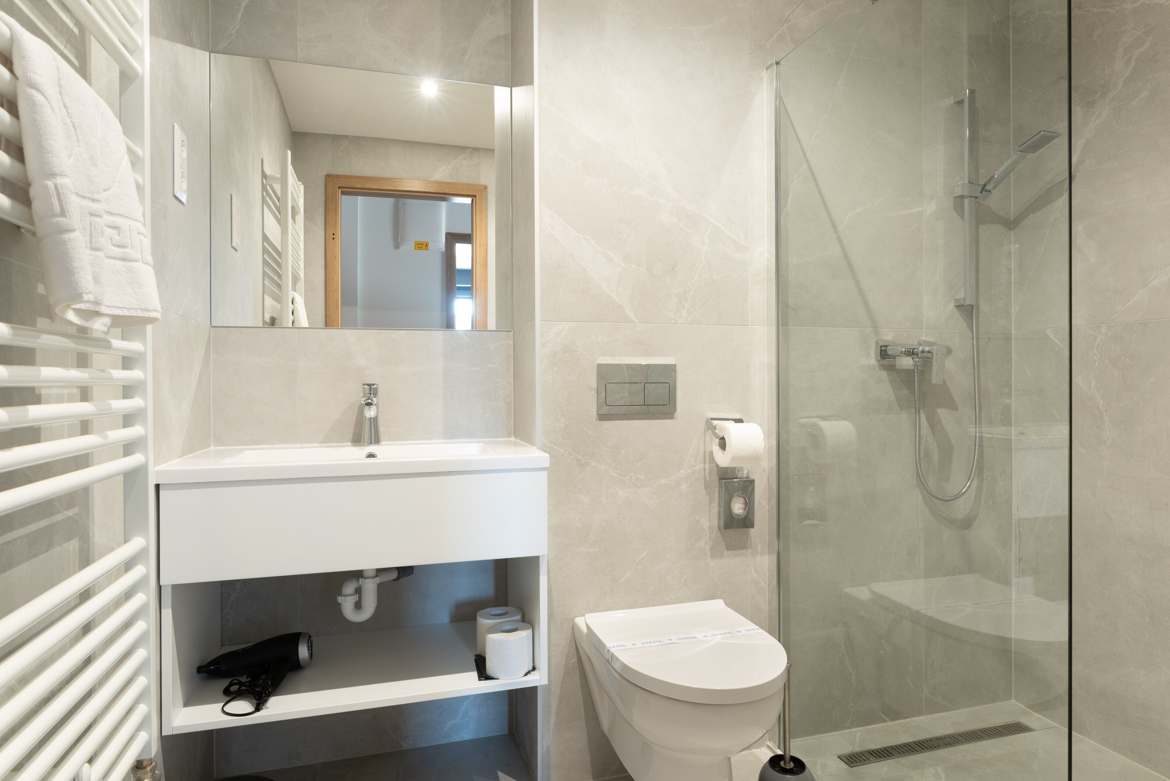 Ein modernes Badezimmer mit Waschbecken, Toilette und einer Duschkabine.