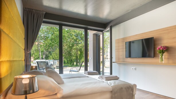 Une chambre d’hôtel moderne, dotée d’un grand lit, d’un téléviseur fixé au mur et offrant une vue sur l’extérieur.