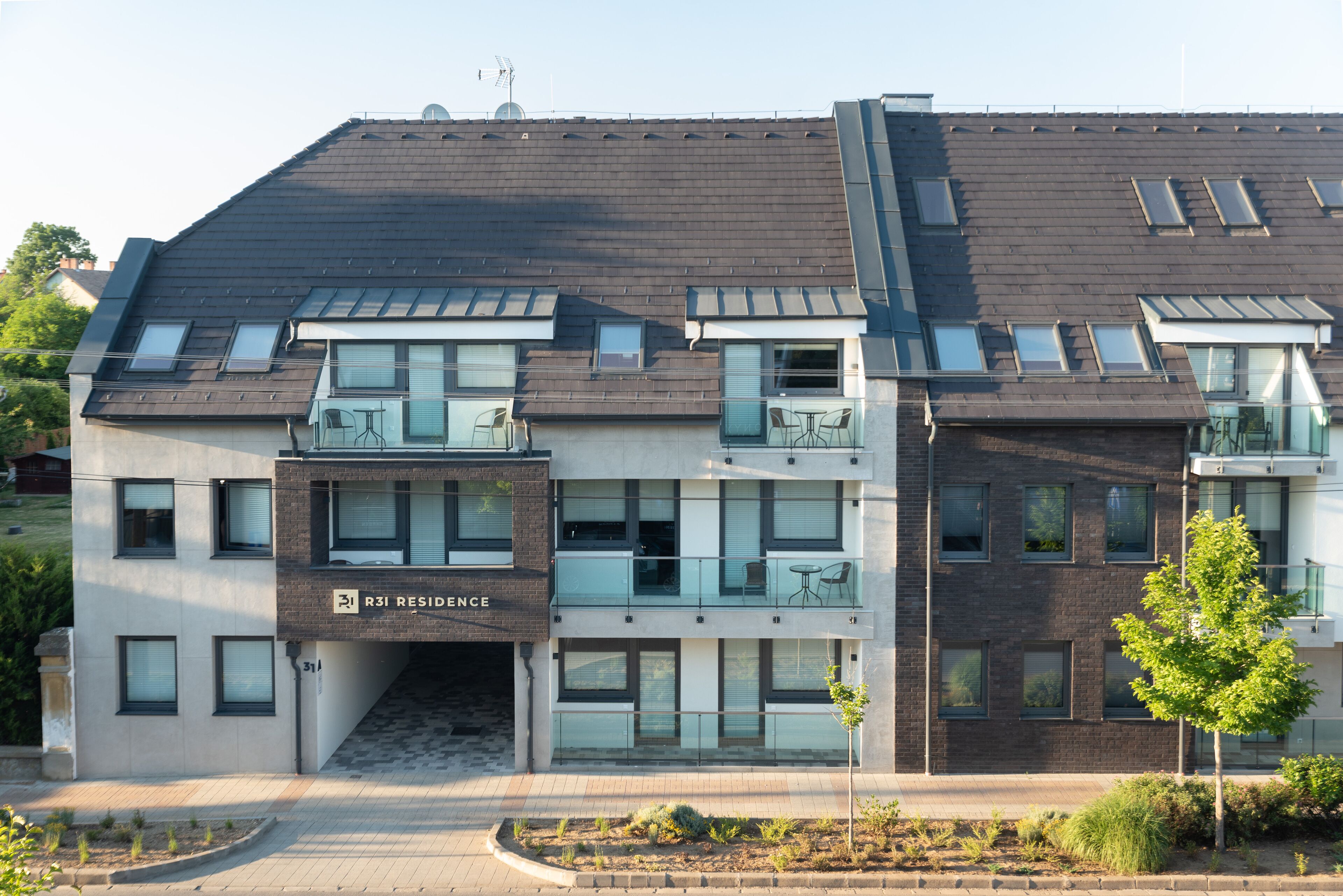 A modern multi-story residential building with a flat roof, large windows, and balconies.
