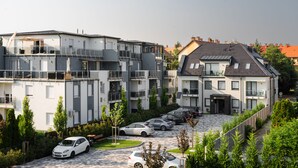 Un immeuble résidentiel à plusieurs étages, doté de balcons, d’un espace de stationnement et d’un jardin.