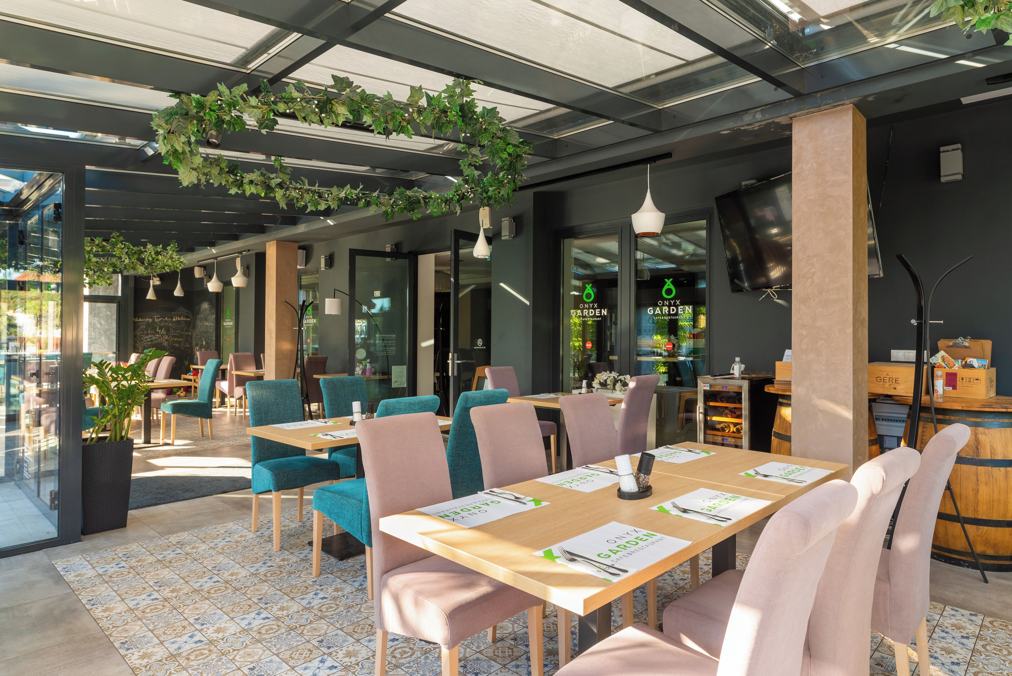 Un espace de restauration intérieur avec des tables et des chaises, une grande plante en pot et des plantes suspendues.