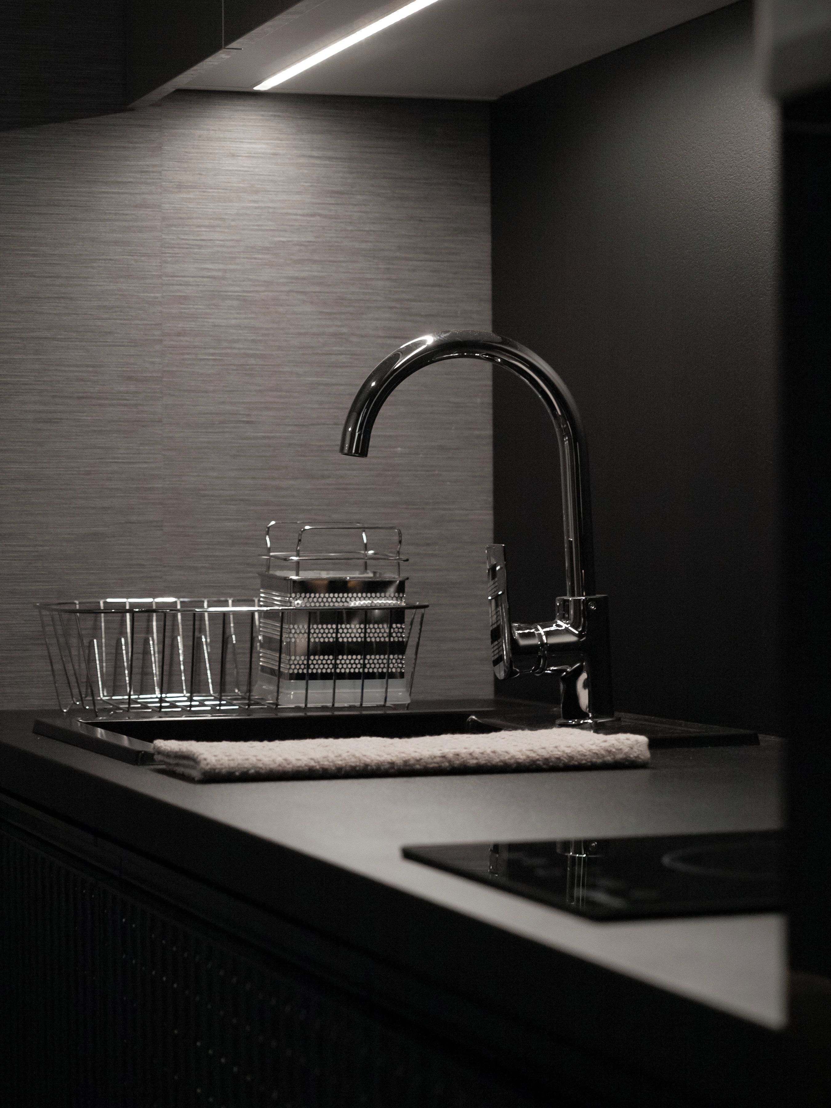 A modern kitchen with a sleek faucet, a glass dish rack, and a countertop.