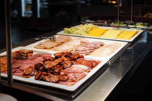 A buffet with various meats and cheeses.