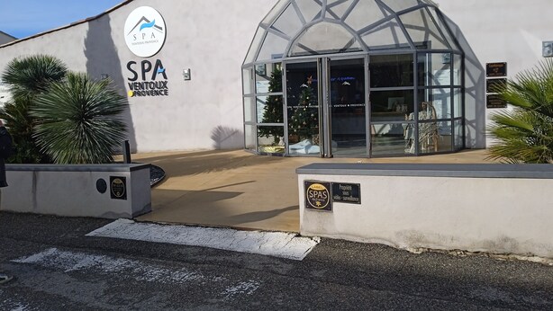 Un bâtiment abritant un centre de bien-être, doté d’une entrée en verre, d’une enseigne indiquant « SPA VINTOUX PROVENCE » et de caméras de surveillance.