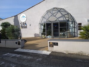 Edificio de spa con entrada de vidrio, señalización SPA VINTOUX PROVENCE y cámaras de seguridad.