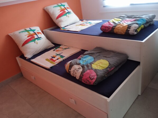 Una cama individual con dos almohadas, una manta y una funda de almohada con un diseño colorido.