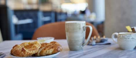 A table with croissants, a mug, and a cup, likely in a cafe setting.