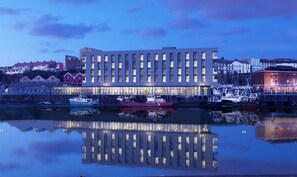 Een modern gebouw met een reflecterend wateroppervlak ervoor.