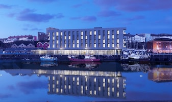 Un edificio moderno con una superficie acuática reflectante al frente.