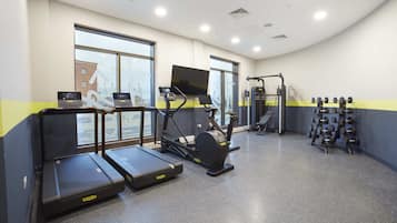 A gym with treadmills, an elliptical, a weight rack, and a TV screen.