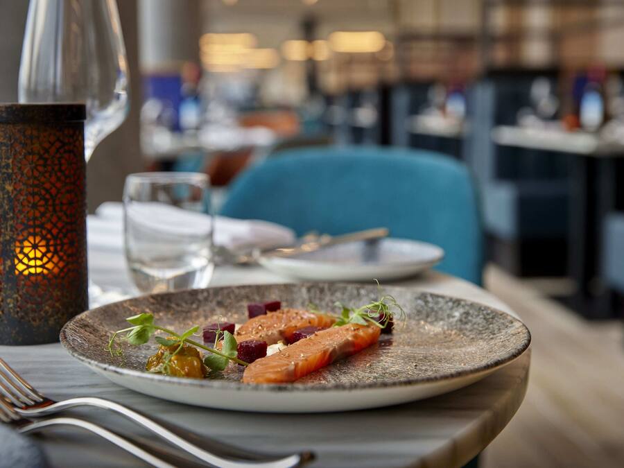 Une table à manger avec une assiette de nourriture, une bougie et des couverts.
