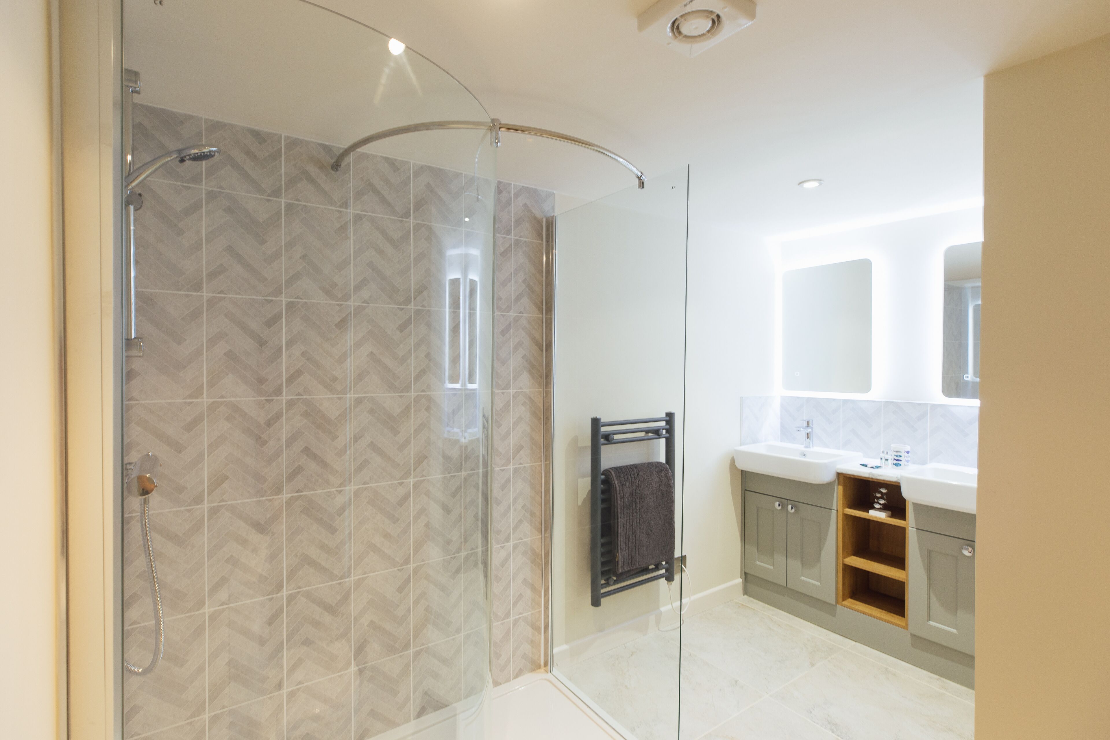 A modern bathroom with a glass shower enclosure, a towel rack, and a vanity with a mirror.