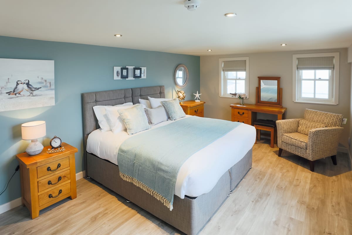 Ein Schlafzimmer mit einem großen Bett, Nachttischen, einem Sessel und Bildern an der Wand.