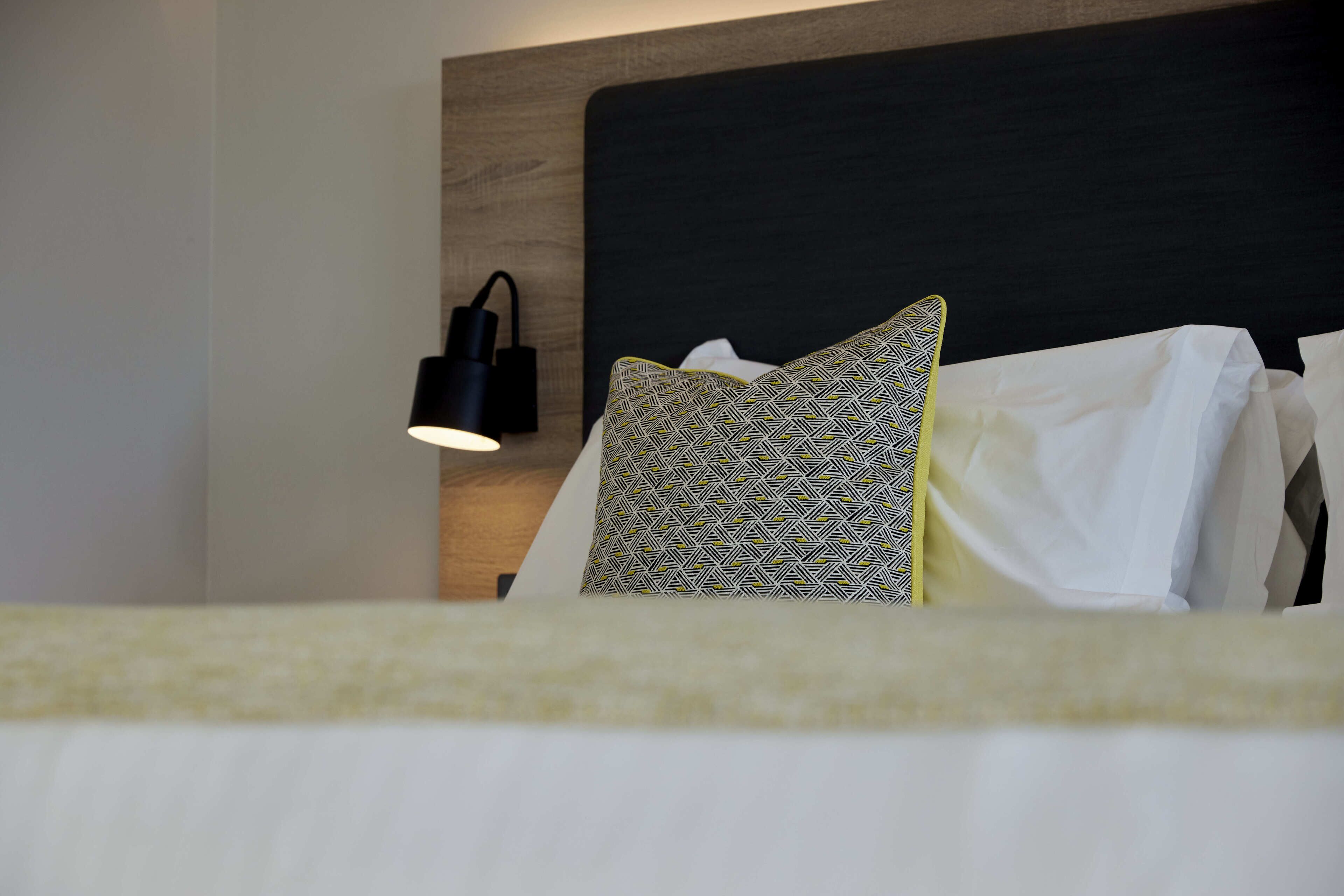 A neatly made bed with patterned pillows and a black headboard.