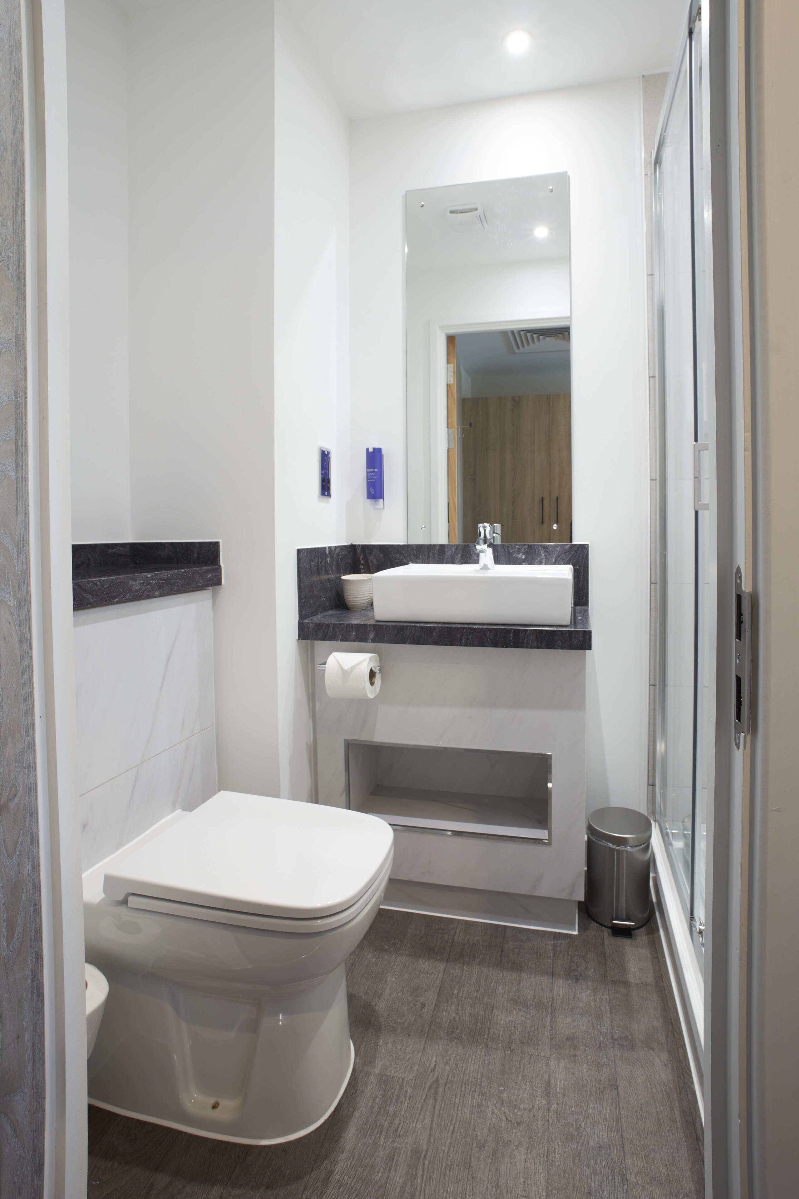 Ein modernes Badezimmer mit Toilette, Waschbecken und Spiegel.