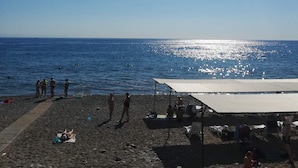 A beach with people, a tent, and a parasail in the distance. - Santana Hotel (Kemer)
