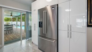 A modern kitchen with stainless steel appliances, a glass door leading to an outdoor area with a pool, and a ceiling fan. - 8 minutes from the AIRPORT~ New SaL POOL - WiFi 1gbps/free Parking... BBQ (Tampa)