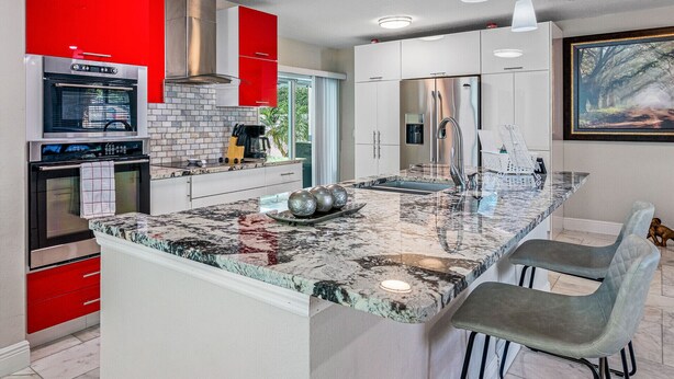 A modern kitchen with a marble island, stainless steel appliances, and red accents. - 8 minutes from the AIRPORT~ New SaL POOL - WiFi 1gbps/free Parking... BBQ (Tampa)