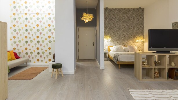 A modern living room with a sofa, a small stool, a television, and a wall with a floral pattern. - Modern apartment in the historic center !!! (Zaragoza)