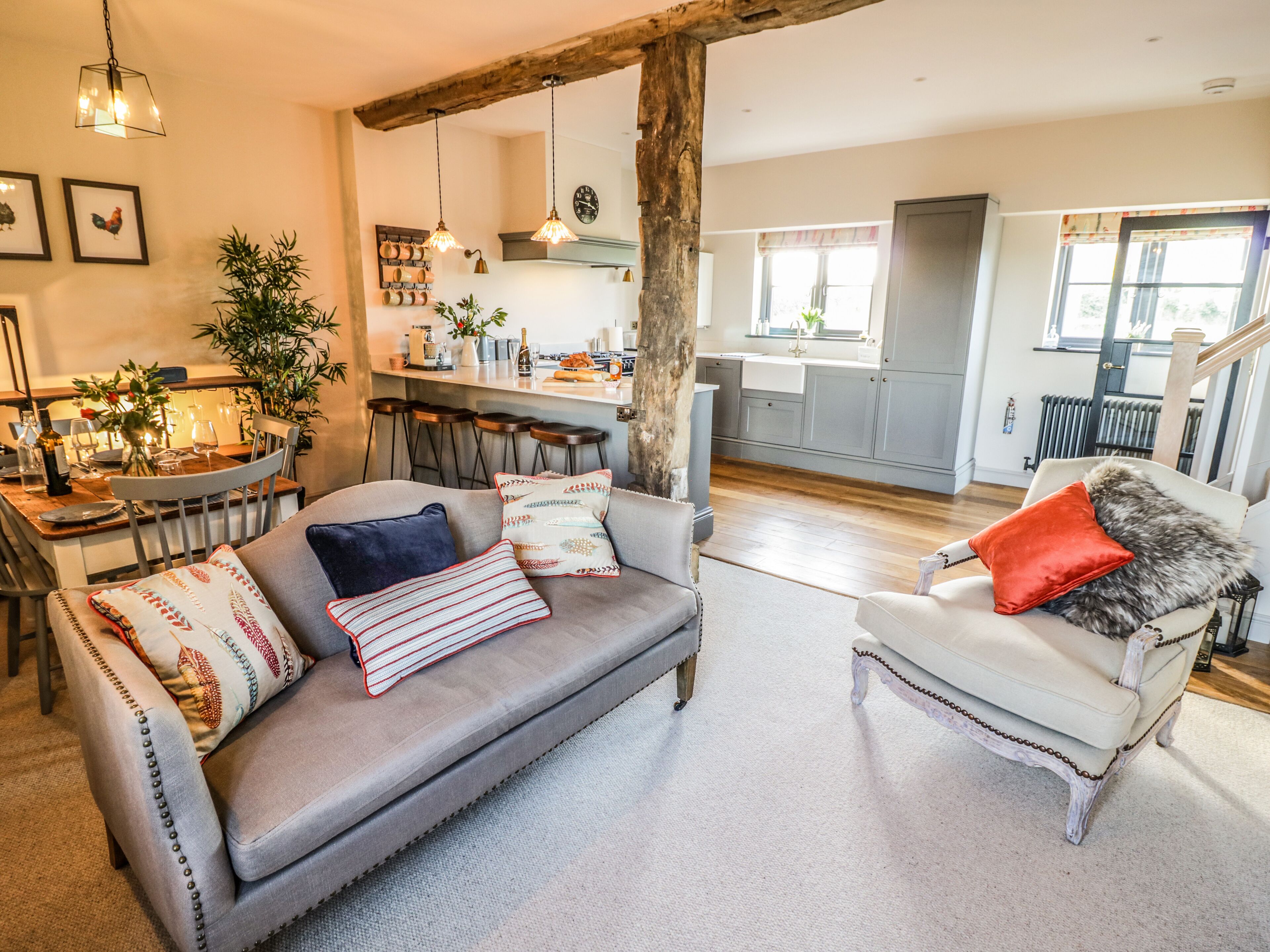 A cozy living room with a grey sofa, a white armchair, and a dining area with a wooden table and chairs.