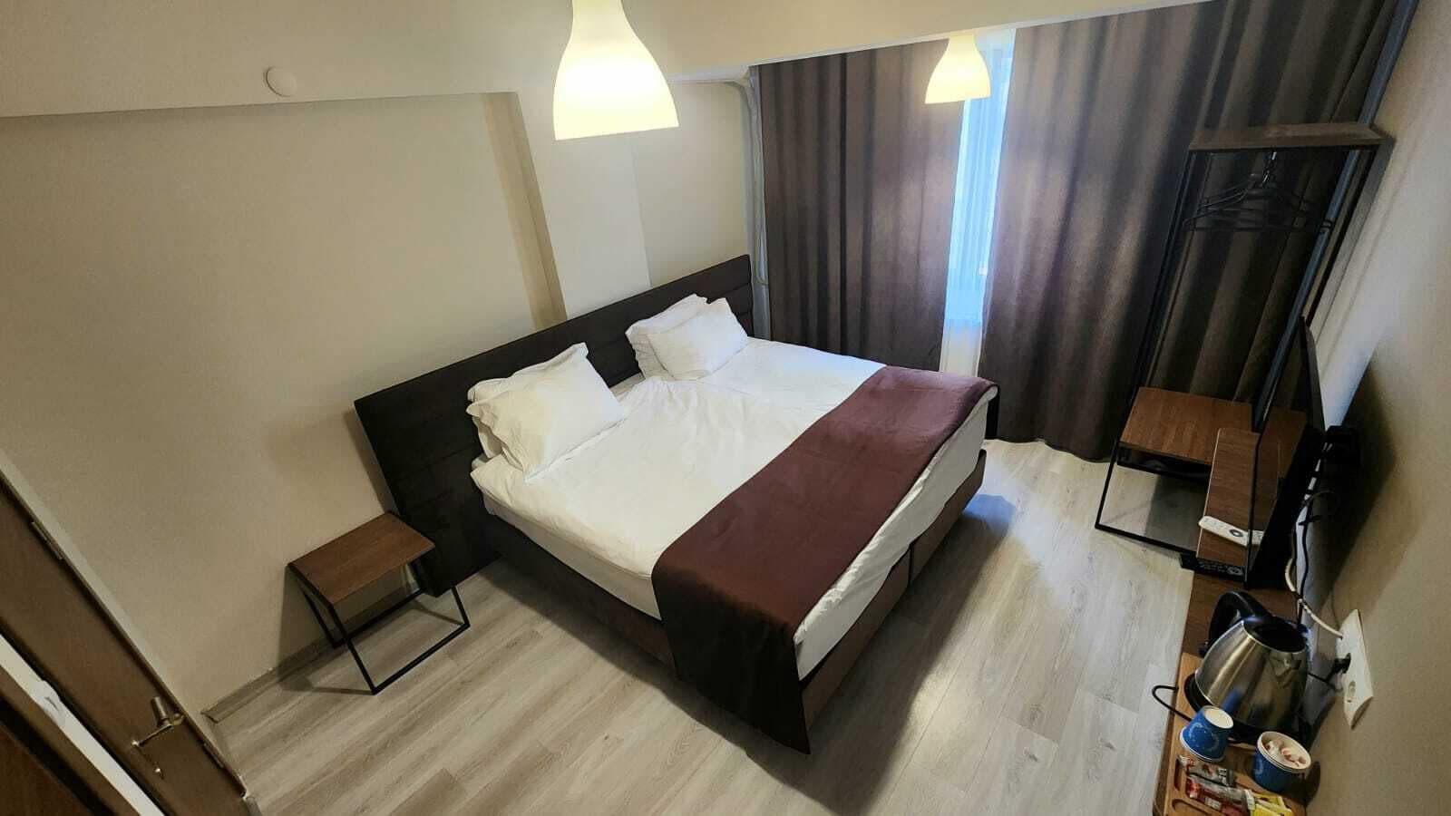Ein Hotelzimmer mit Bett, Nachttischen, einem Spiegel und einem Kleiderschrank.