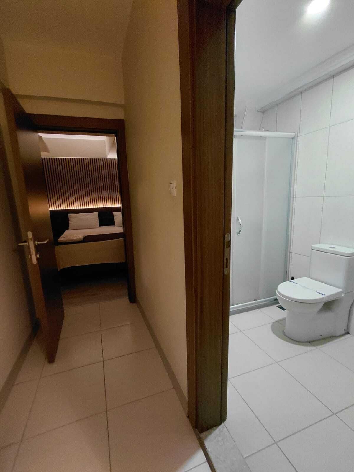 Un baño con inodoro, ducha y cama con cabecera.