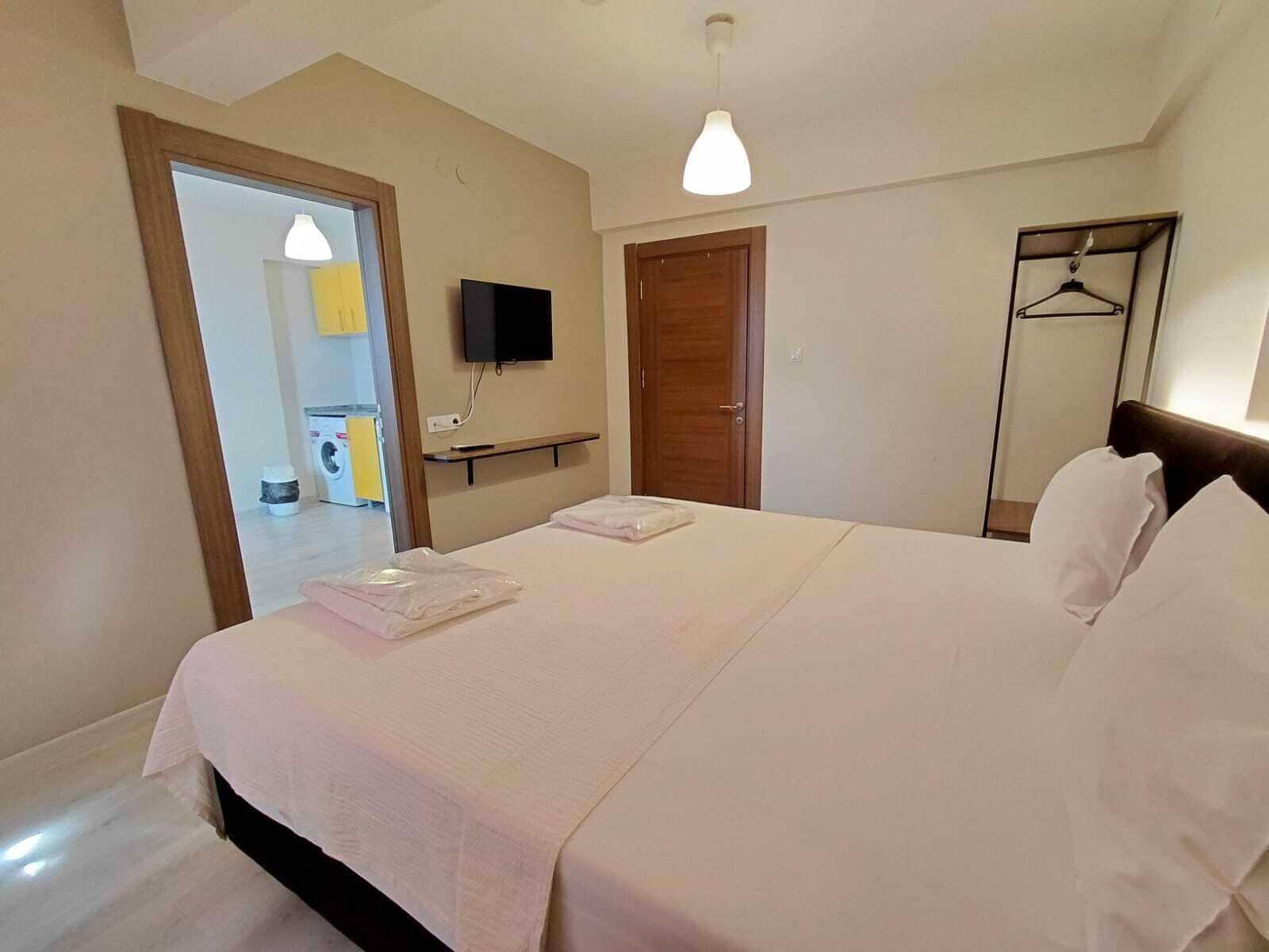 Una habitación de hotel con una cama, televisión, armario y espejo.