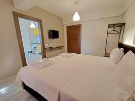 Una habitación de hotel con una cama, televisión, armario y espejo.