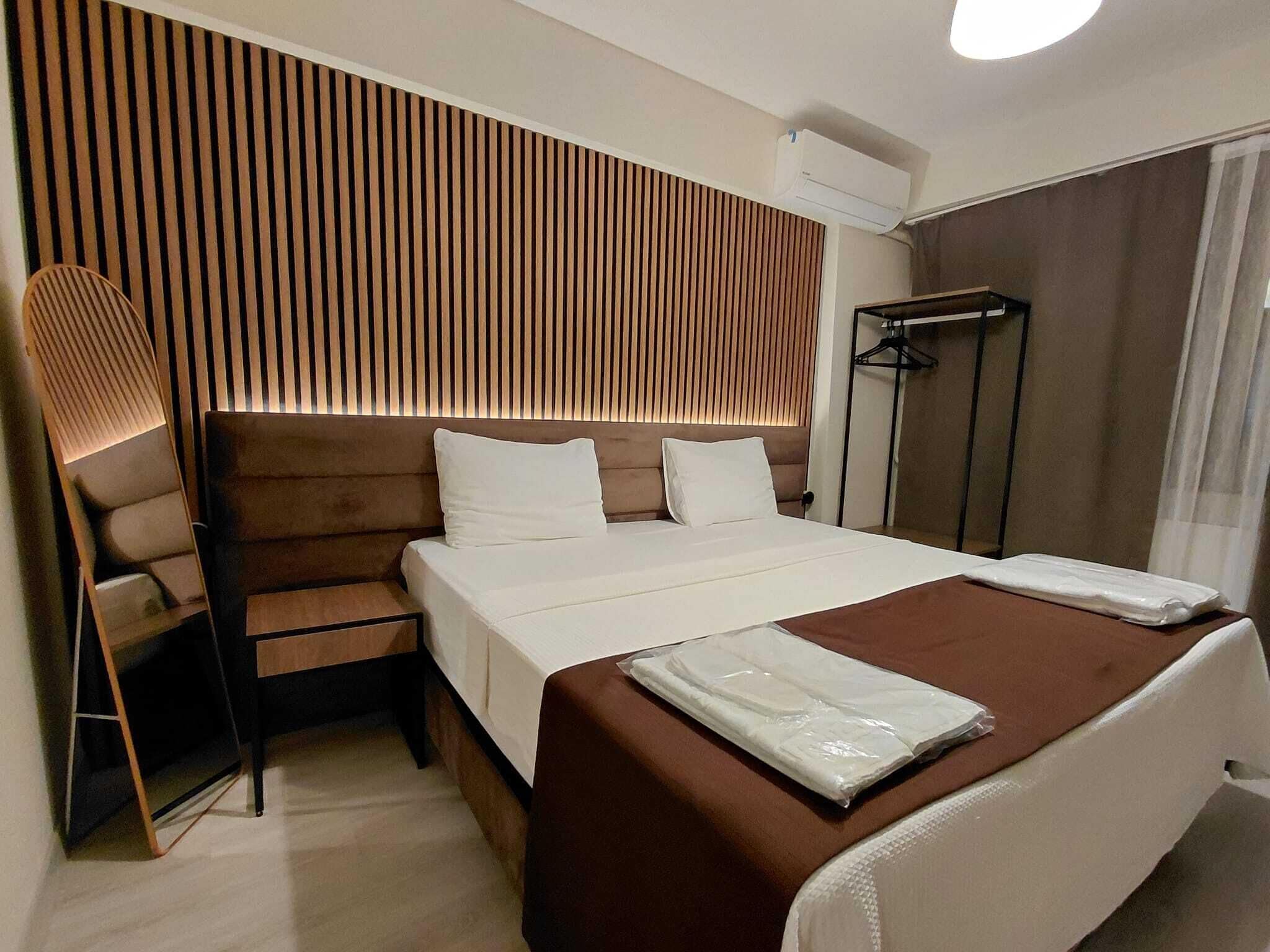Habitación de hotel con cama, zona de estar con una silla, armario y cabina de ducha.