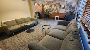 A modern living room with a sofa set, two small round tables, and a patterned carpet.