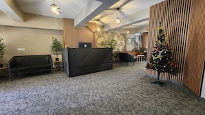 A reception area with a modern desk, a Christmas tree, and a seating area with a sofa and chairs.