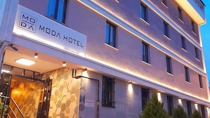 A modern hotel with a sign reading "MODA HOTEL" and a staircase leading to the entrance.