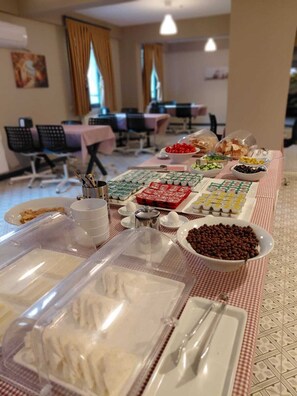 A buffet setup with various food items and utensils on a checkered tablecloth. - Moda Hotel (Kirklareli)