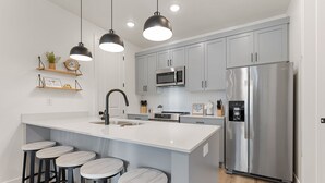 A modern kitchen with a central island, stainless steel appliances, and bar stools. - Desert Retreat #73 by RedAwning (St. George)