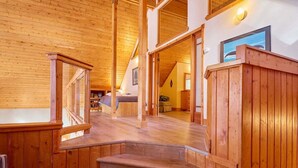 A wooden interior with a staircase leading to a bedroom, a dining area, and a kitchen. - Lakeside Retreat w/Private Sandy Beach and Hot Tub (Leavenworth)