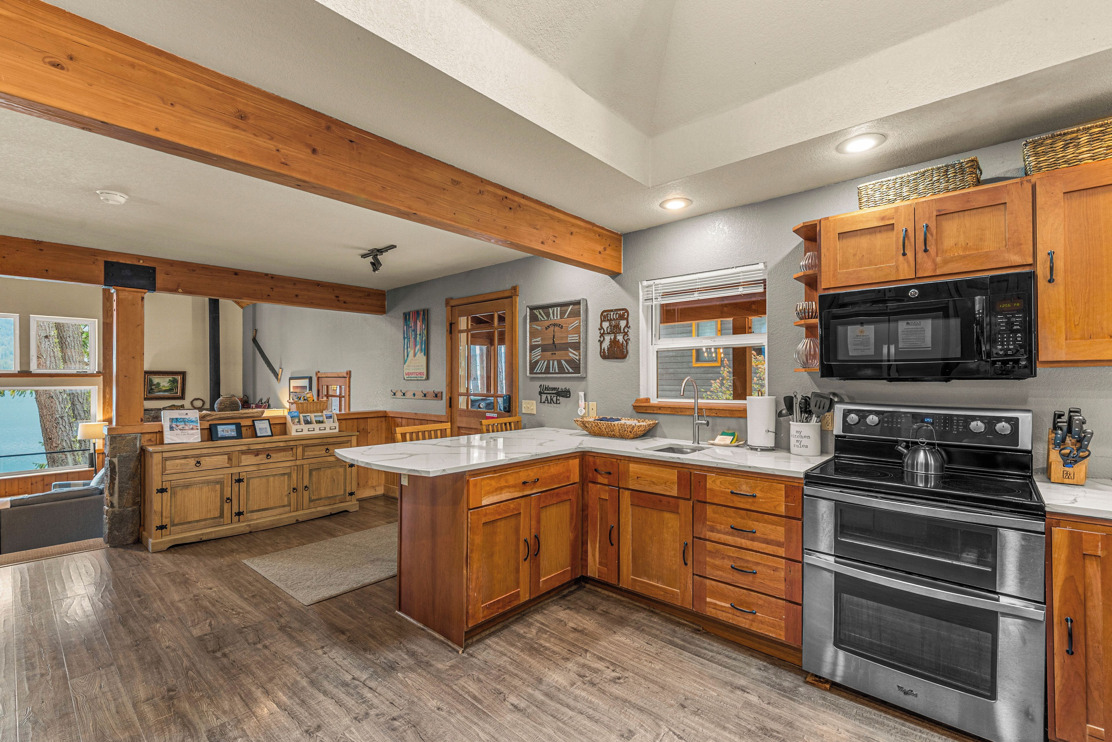 A spacious kitchen with wooden cabinets, a large island, stainless steel appliances, and a view of the outdoors.