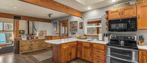 A spacious kitchen with wooden cabinets, a large island, stainless steel appliances, and a view of the outdoors.