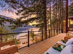 A deck with wicker furniture overlooking a lake and mountains. - Lakeside Retreat w/Private Sandy Beach and Hot Tub (Leavenworth)