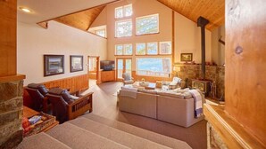 A spacious living area with a fireplace, a television, and a stone fireplace. - Lakeside Retreat w/Private Sandy Beach and Hot Tub (Leavenworth)