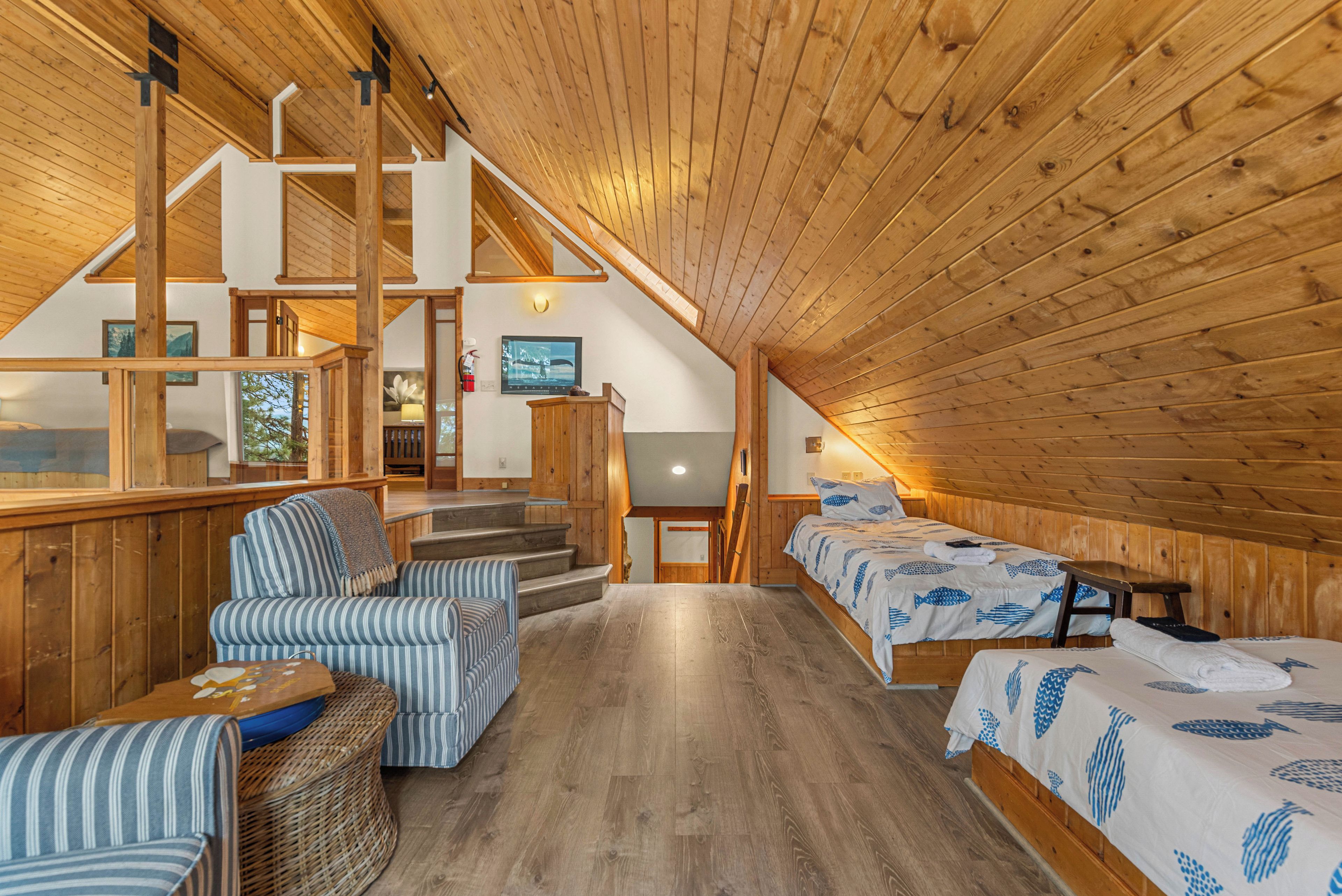 A wooden interior with a staircase, a sofa, a bed, and a television.