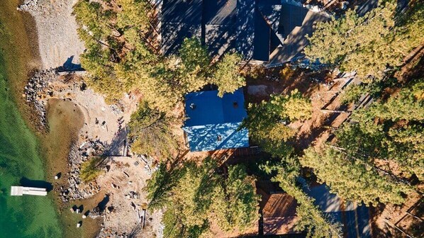 An aerial view of a property with a swimming pool surrounded by trees, a dock, and a rocky shoreline. - Lakeside Retreat w/Private Sandy Beach and Hot Tub (Leavenworth)