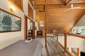 A bedroom with a bed, a desk, and a window overlooking a snowy landscape.