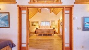 A bedroom with a wooden bed, a nightstand, and a painting on the wall. - Lakeside Retreat w/Private Sandy Beach and Hot Tub (Leavenworth)