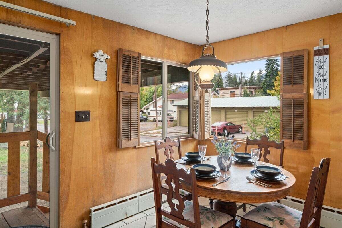 Zona pranzo con tavolo in legno, sedie e lampadario.