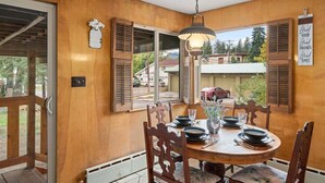 Uma sala de jantar com uma mesa de madeira, cadeiras e um lustre.